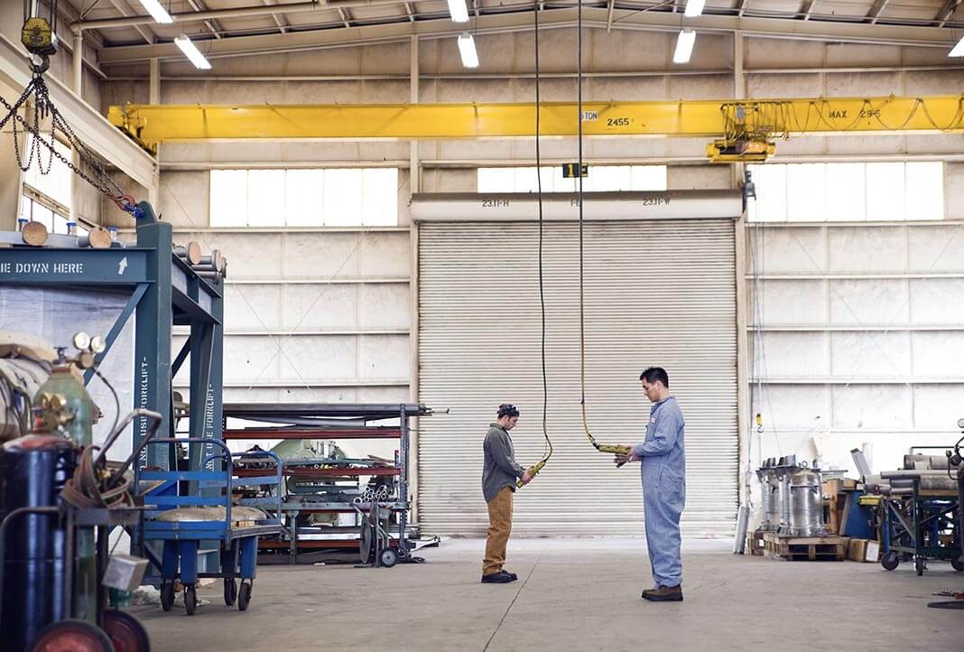 Two factory workers operating gantry cranes